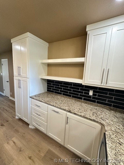 kitchen featuring light hardwood / wood-style flooring, light stone countertops, decorative backsplash, and white cabinetry