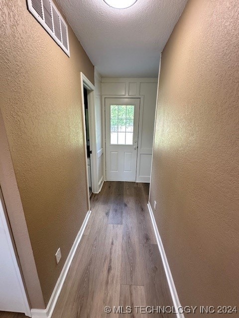 hall featuring a textured ceiling and hardwood / wood-style flooring