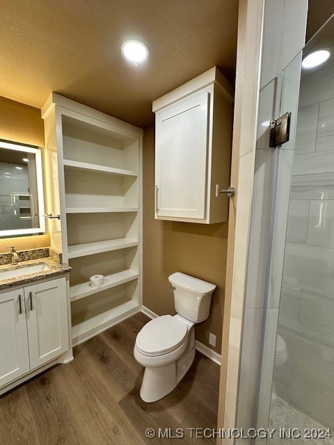 bathroom with a textured ceiling, vanity, toilet, and hardwood / wood-style floors