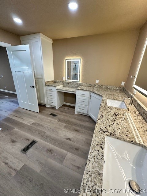 kitchen featuring light hardwood / wood-style flooring, kitchen peninsula, sink, and white cabinetry