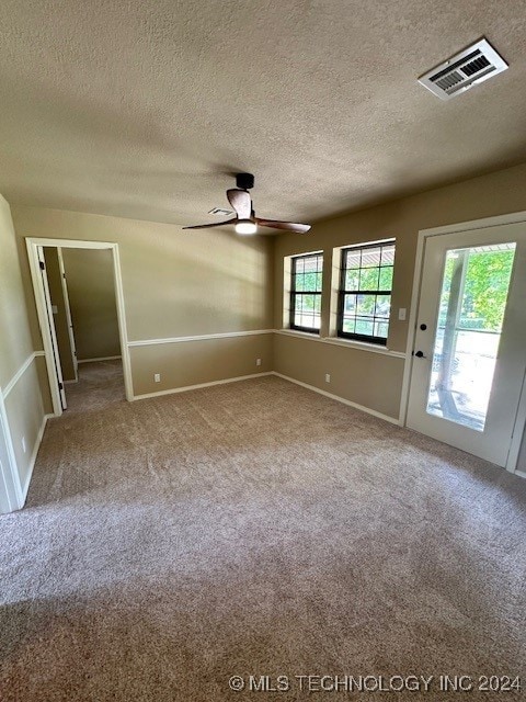 spare room featuring ceiling fan, light carpet, and a textured ceiling