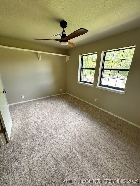 carpeted spare room featuring a textured ceiling and ceiling fan