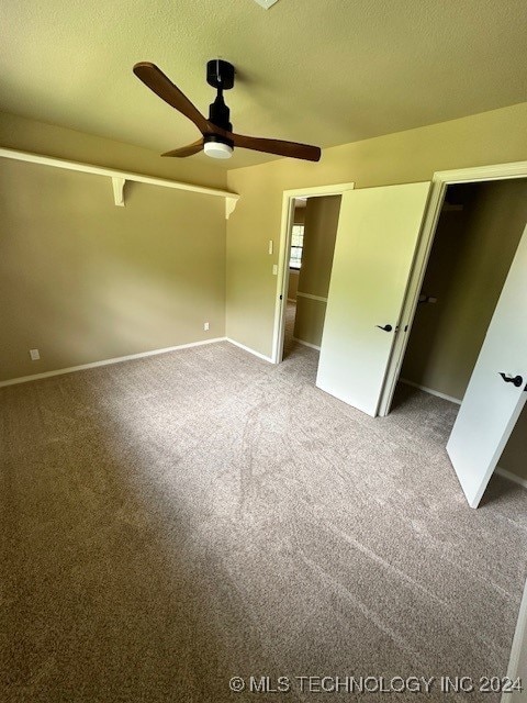 unfurnished bedroom with a textured ceiling, ceiling fan, a closet, and carpet floors