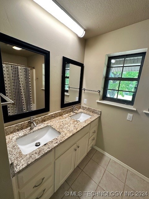 bathroom featuring a textured ceiling, vanity, and tile patterned floors