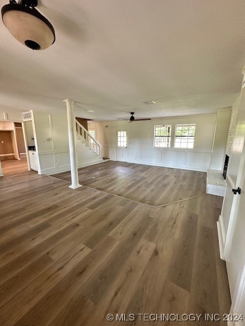 interior space featuring decorative columns, hardwood / wood-style flooring, and ceiling fan