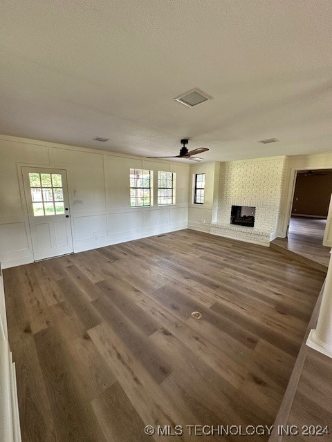 unfurnished living room featuring ceiling fan, a fireplace, and dark hardwood / wood-style flooring