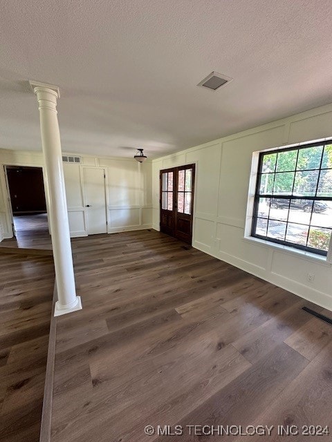 interior space featuring a textured ceiling, dark hardwood / wood-style flooring, and decorative columns