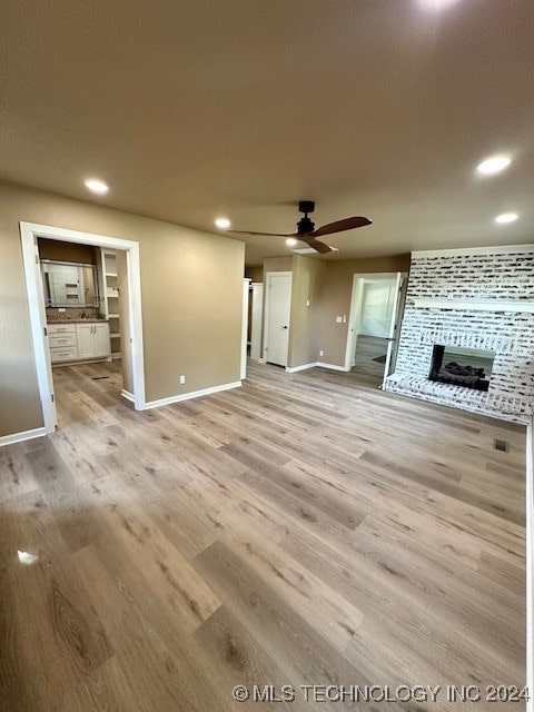 unfurnished living room featuring a textured ceiling, ceiling fan, light wood-type flooring, and a fireplace