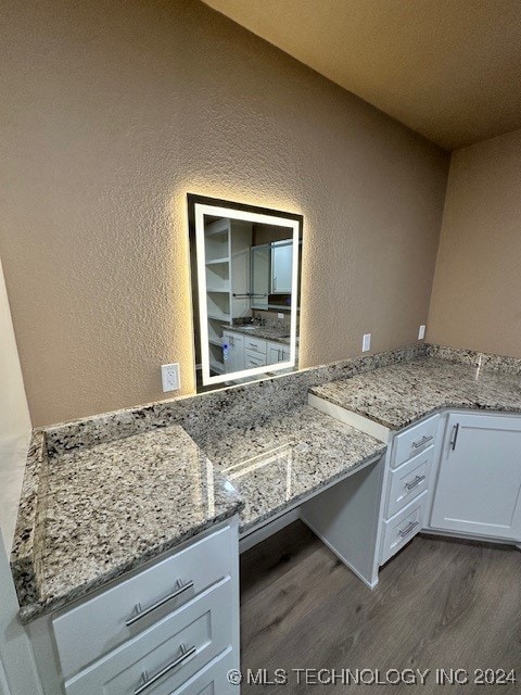 kitchen featuring white cabinetry, hardwood / wood-style flooring, and light stone counters