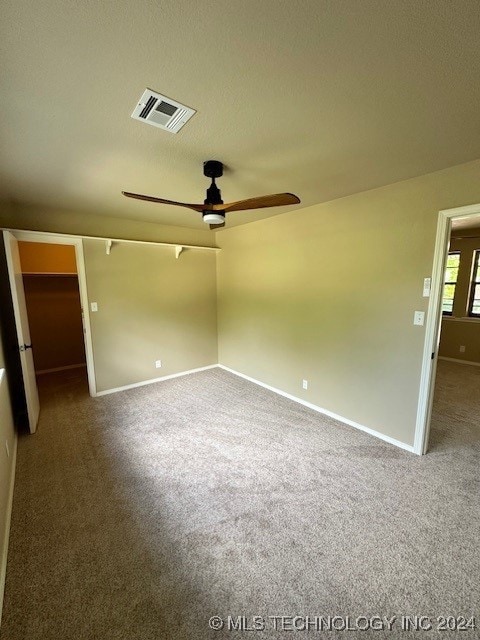 unfurnished bedroom featuring a textured ceiling, carpet flooring, ceiling fan, and a spacious closet