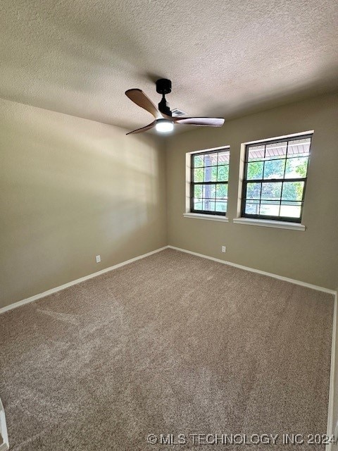 empty room with ceiling fan, carpet, and a textured ceiling