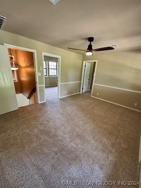 carpeted spare room featuring ceiling fan and a textured ceiling