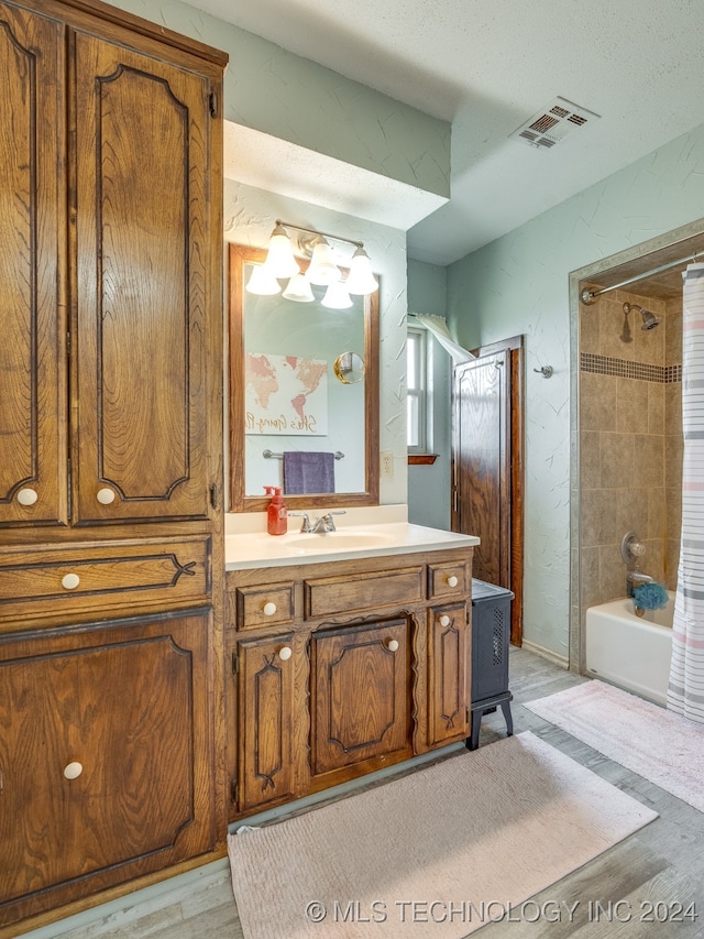 bathroom with vanity, a textured ceiling, shower / tub combo with curtain, and hardwood / wood-style flooring