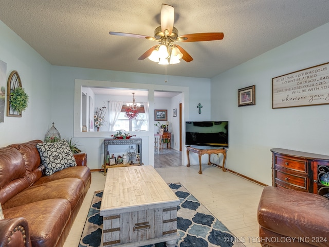 living room featuring a textured ceiling and ceiling fan with notable chandelier