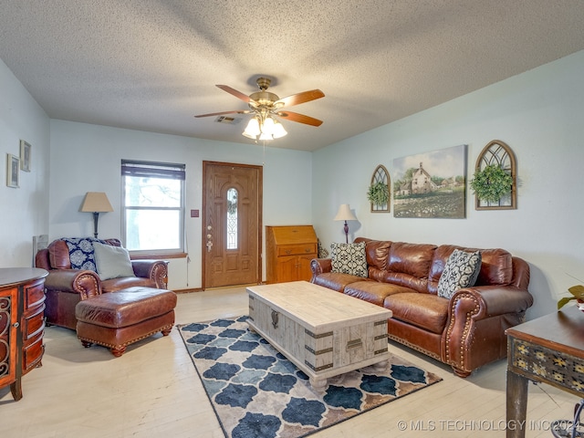 living room featuring a textured ceiling, ceiling fan, and light wood-type flooring