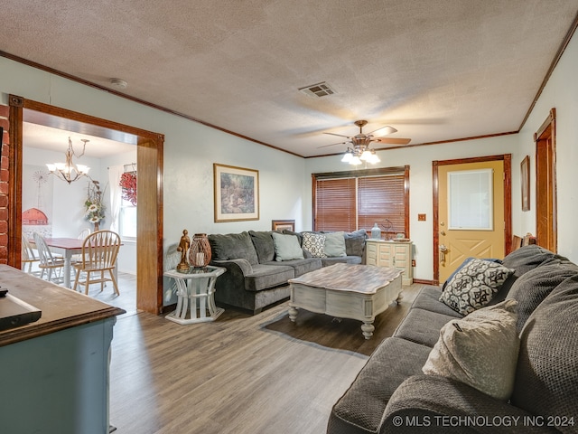 living room with a textured ceiling, crown molding, ceiling fan with notable chandelier, and wood-type flooring