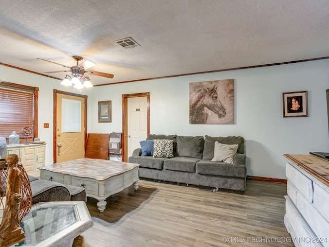 living room featuring a textured ceiling, ceiling fan, ornamental molding, and hardwood / wood-style flooring