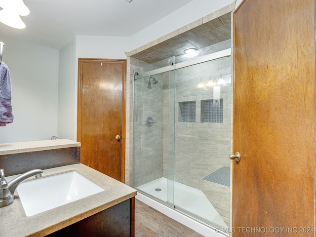 bathroom with wood-type flooring, a shower with door, and vanity