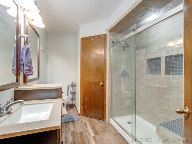 bathroom featuring vanity, toilet, hardwood / wood-style flooring, and an enclosed shower