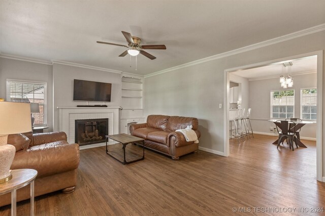 living room with hardwood / wood-style floors, ceiling fan with notable chandelier, a wealth of natural light, and crown molding