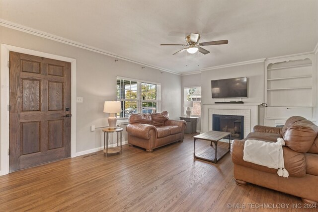 living room with ceiling fan, hardwood / wood-style flooring, a fireplace, and crown molding