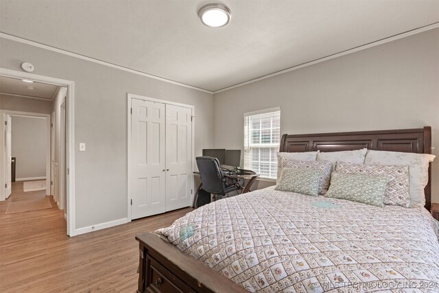 bedroom featuring light wood-type flooring, a closet, and ornamental molding