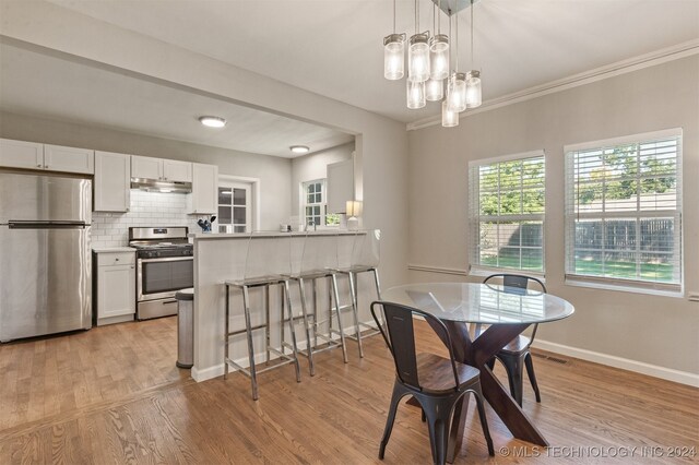 dining area featuring ornamental molding, a chandelier, and light hardwood / wood-style floors