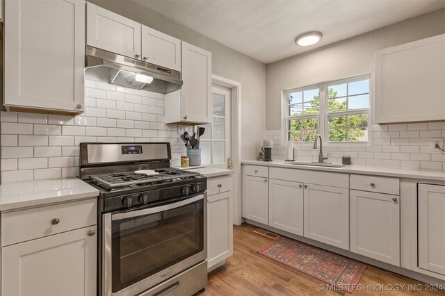 kitchen featuring light wood-type flooring, white cabinets, gas range, and sink