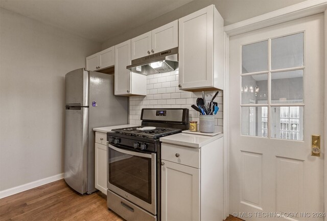 kitchen with decorative backsplash, stainless steel appliances, white cabinets, and light hardwood / wood-style floors