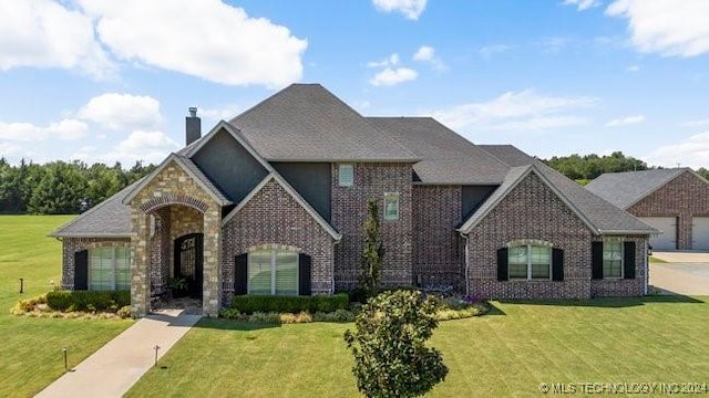 3526 Evans Ave, Mannford, OK 74044 - french provincial home with brick siding, a chimney, a front lawn, and stone siding