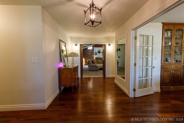 hall featuring an inviting chandelier, a textured ceiling, and dark hardwood / wood-style flooring