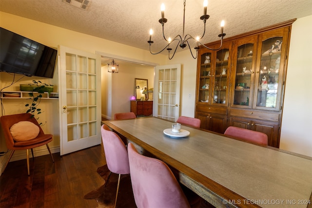 dining room with an inviting chandelier, a textured ceiling, and dark wood-type flooring