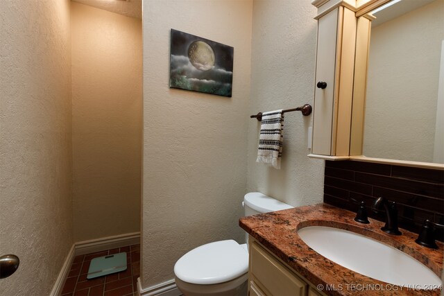 bathroom with tile patterned flooring, vanity, toilet, and tasteful backsplash