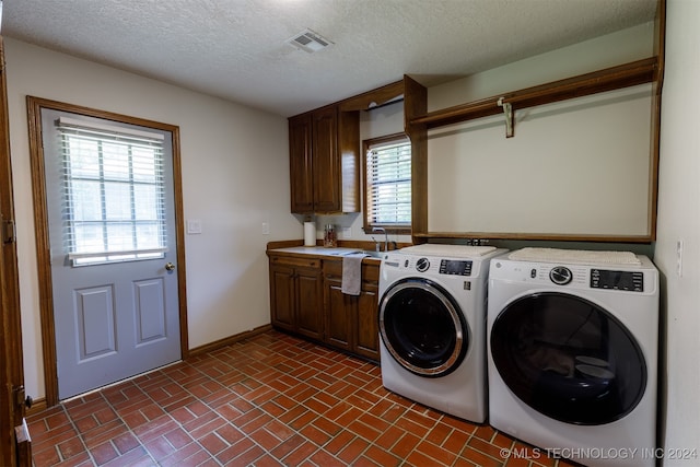 washroom featuring a textured ceiling, sink, independent washer and dryer, and cabinets