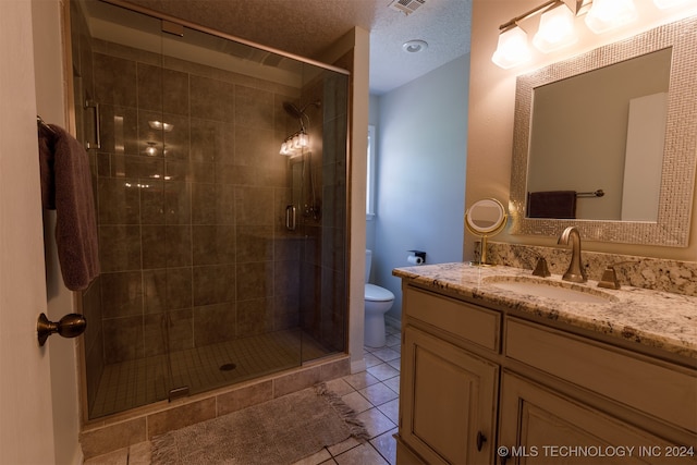 bathroom featuring vanity, toilet, a textured ceiling, walk in shower, and tile patterned flooring