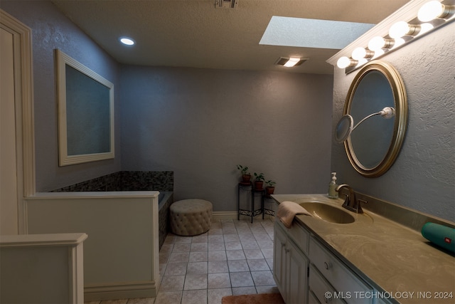 bathroom featuring vanity, a skylight, tile patterned flooring, and a textured ceiling