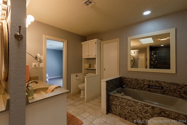 full bathroom with tile patterned floors, a textured ceiling, vanity, and toilet