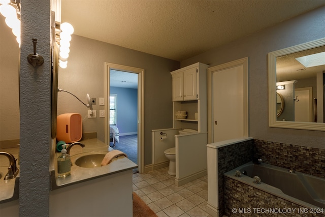 bathroom with a skylight, vanity, a tub, a textured ceiling, and toilet