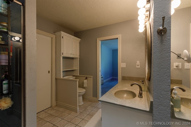 bathroom with a textured ceiling, tile patterned flooring, vanity, and toilet