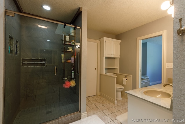 bathroom with a textured ceiling, vanity, toilet, and an enclosed shower