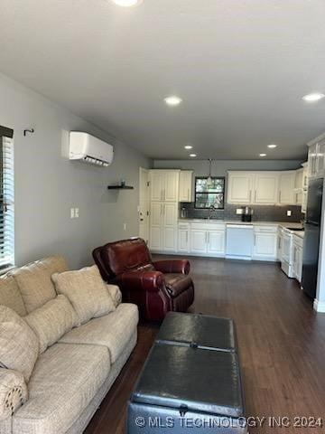 living room with an AC wall unit, dark wood-type flooring, and sink