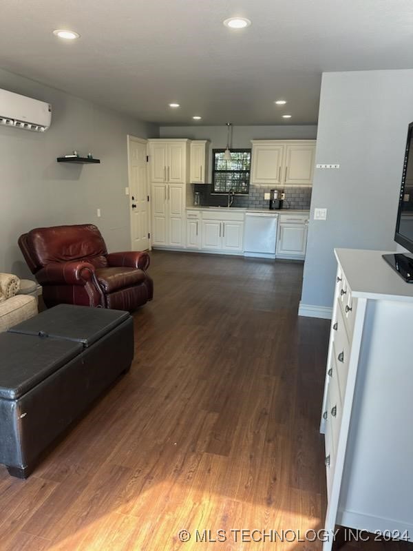 living room featuring sink, dark wood-type flooring, and a wall mounted AC