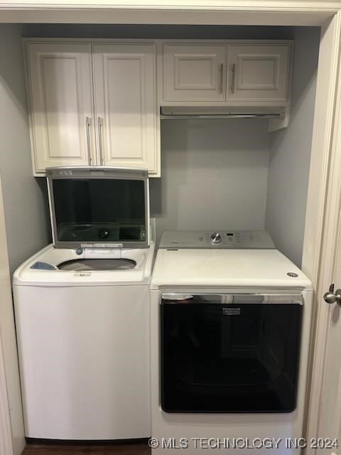 clothes washing area featuring cabinets and washer and dryer