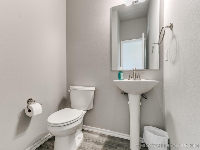 half bathroom featuring toilet, baseboards, and wood finished floors