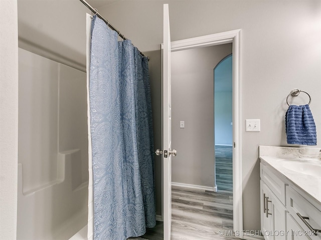 bathroom featuring a shower with curtain, baseboards, wood finished floors, and vanity