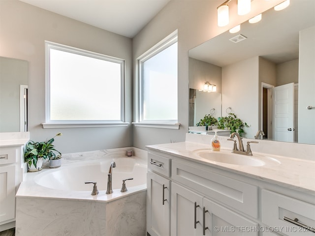 bathroom featuring vanity and a relaxing tiled tub