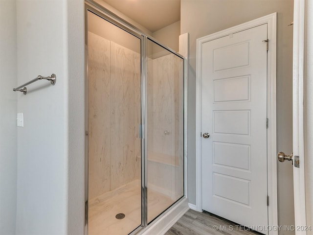 bathroom with a stall shower and wood finished floors