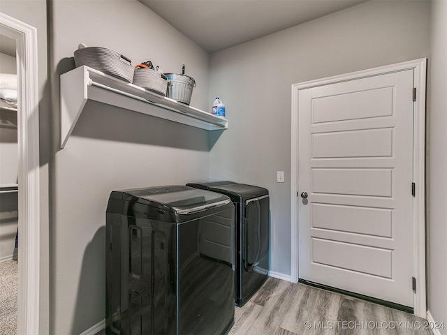 laundry area featuring laundry area, baseboards, light wood-style flooring, and washing machine and clothes dryer