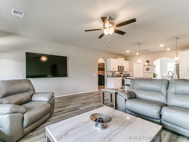 living room with light wood finished floors, visible vents, arched walkways, ceiling fan, and recessed lighting