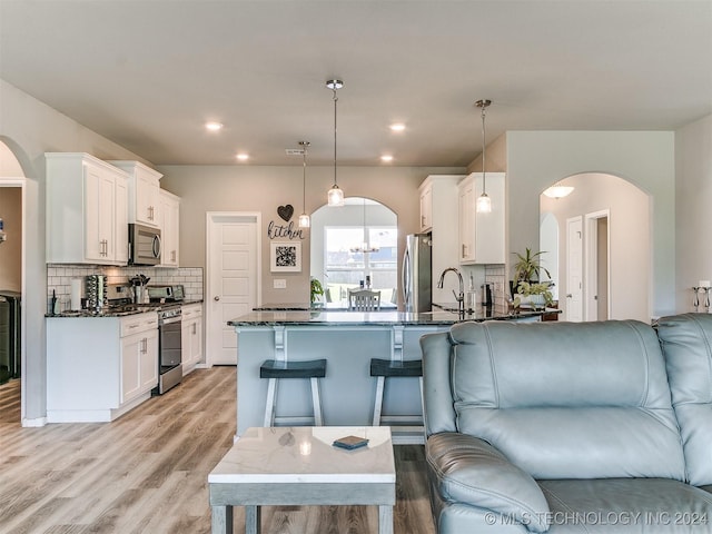 kitchen with a peninsula, arched walkways, stainless steel appliances, and open floor plan